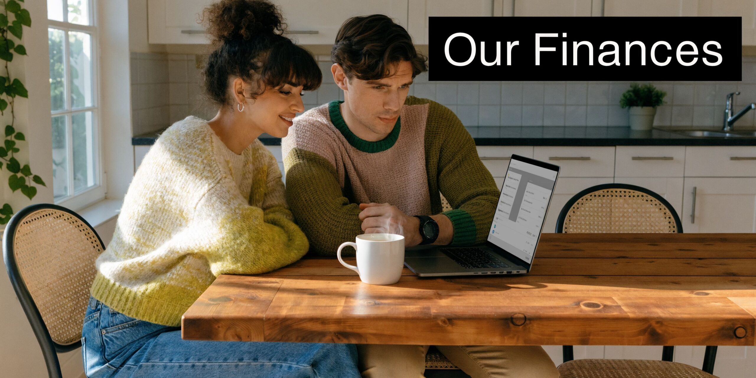 A happy young couple looking at their joint financial planning on a laptop in the kitchen.
