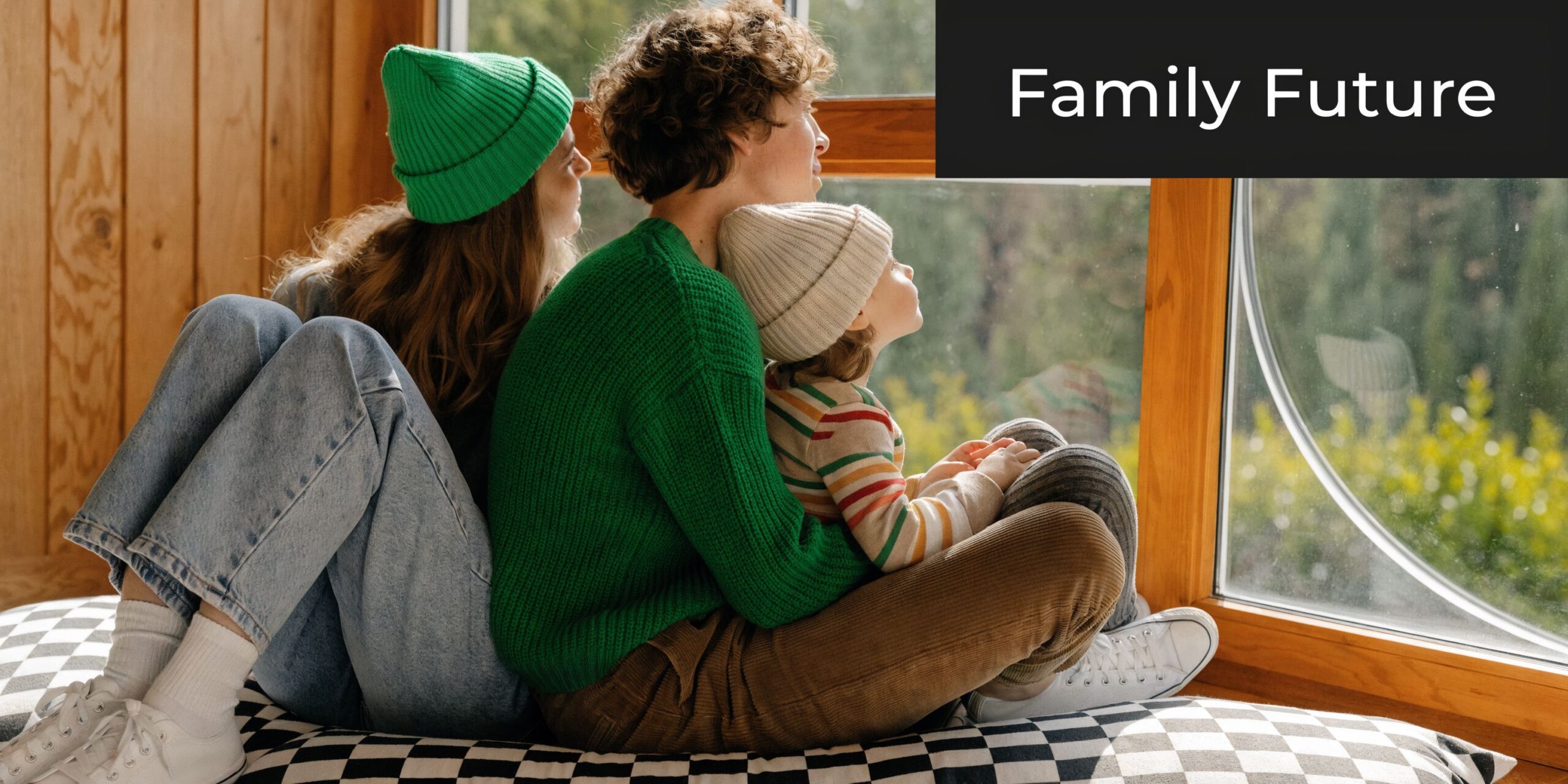 A family of three, including a child, sitting by a large window looking out at nature.