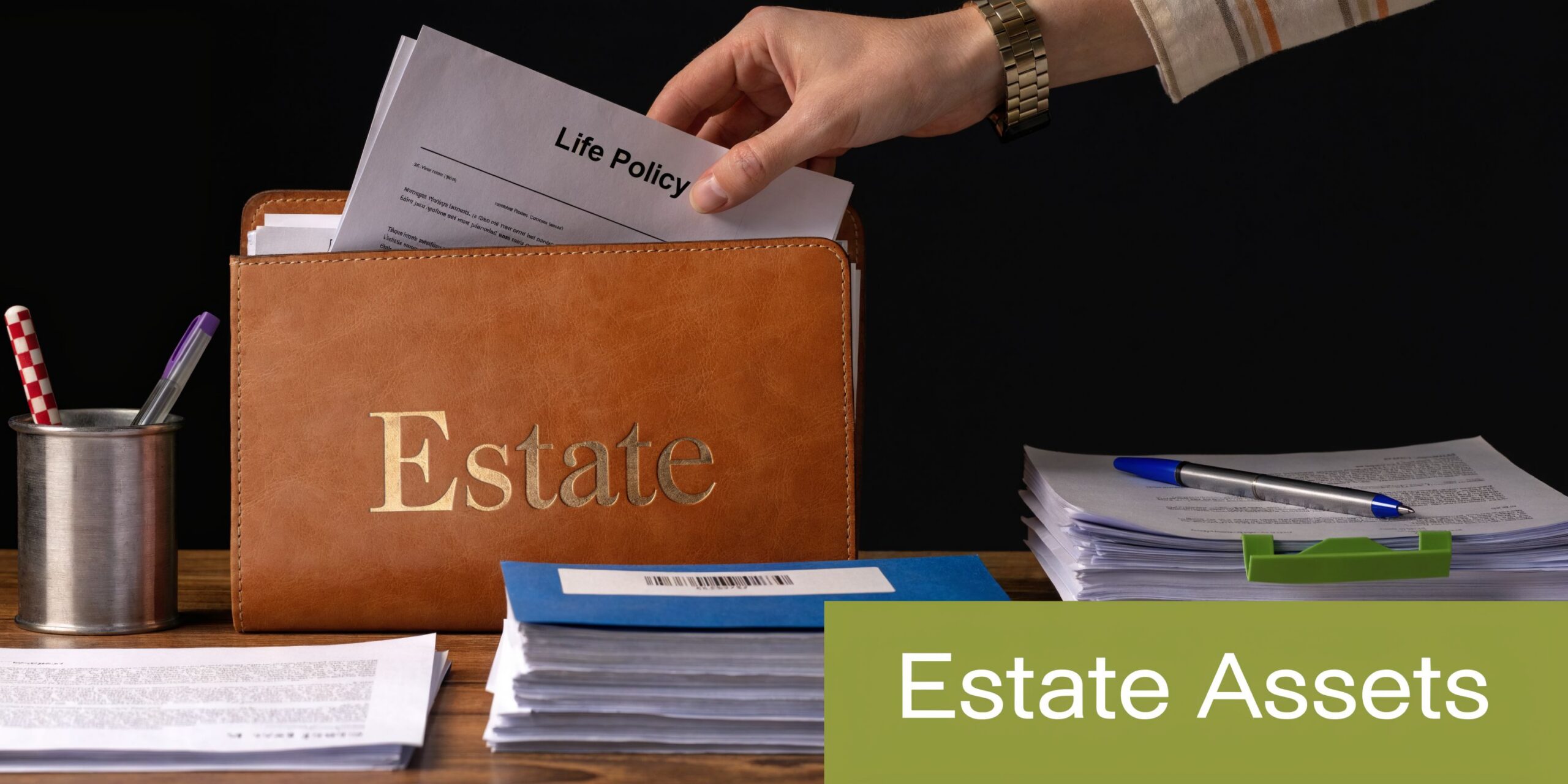 A person organizing legal documents and life insurance policies into an estate planning folder on a desk.