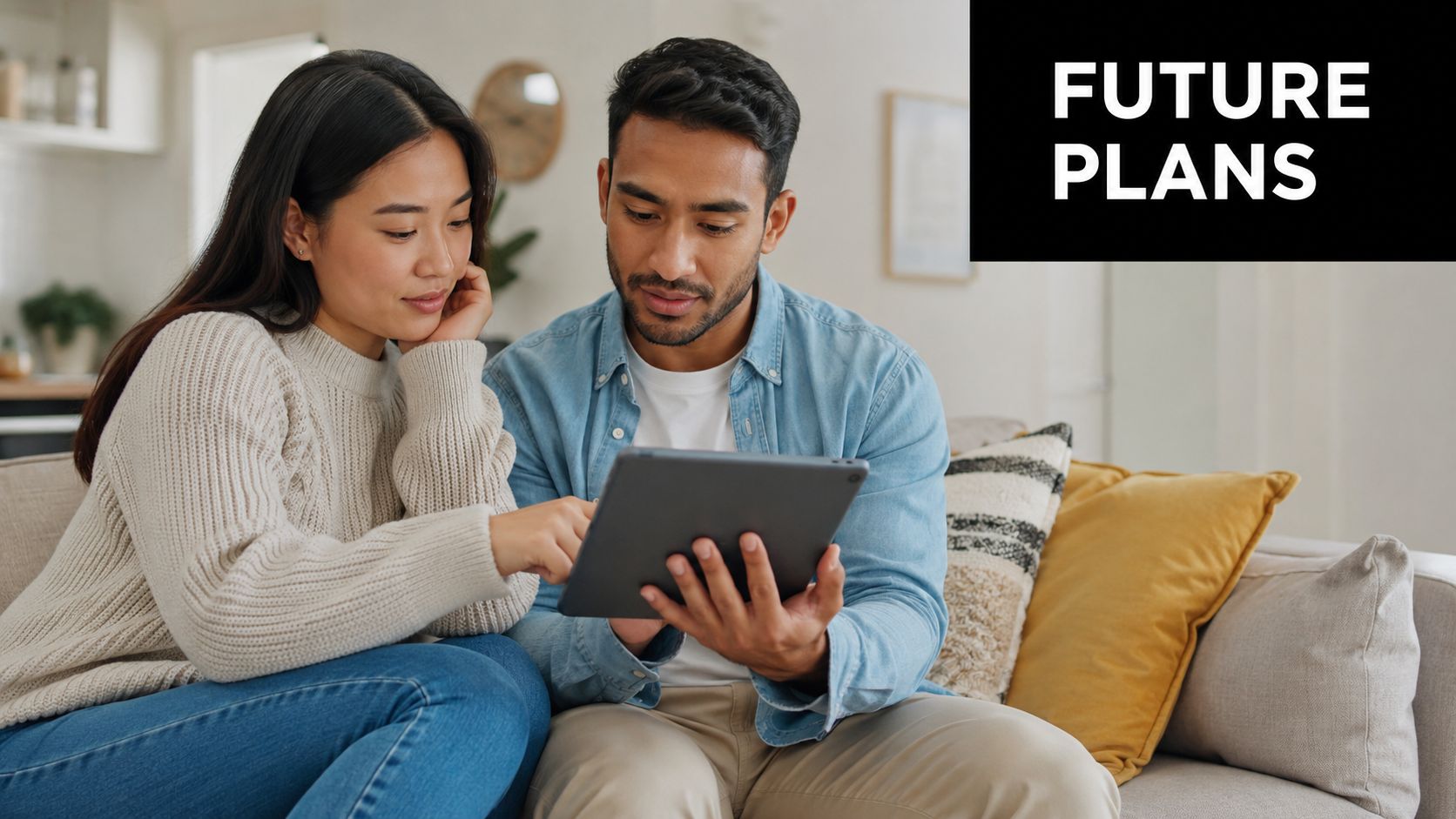A young couple sitting on a couch together while reviewing financial documents on a digital tablet.