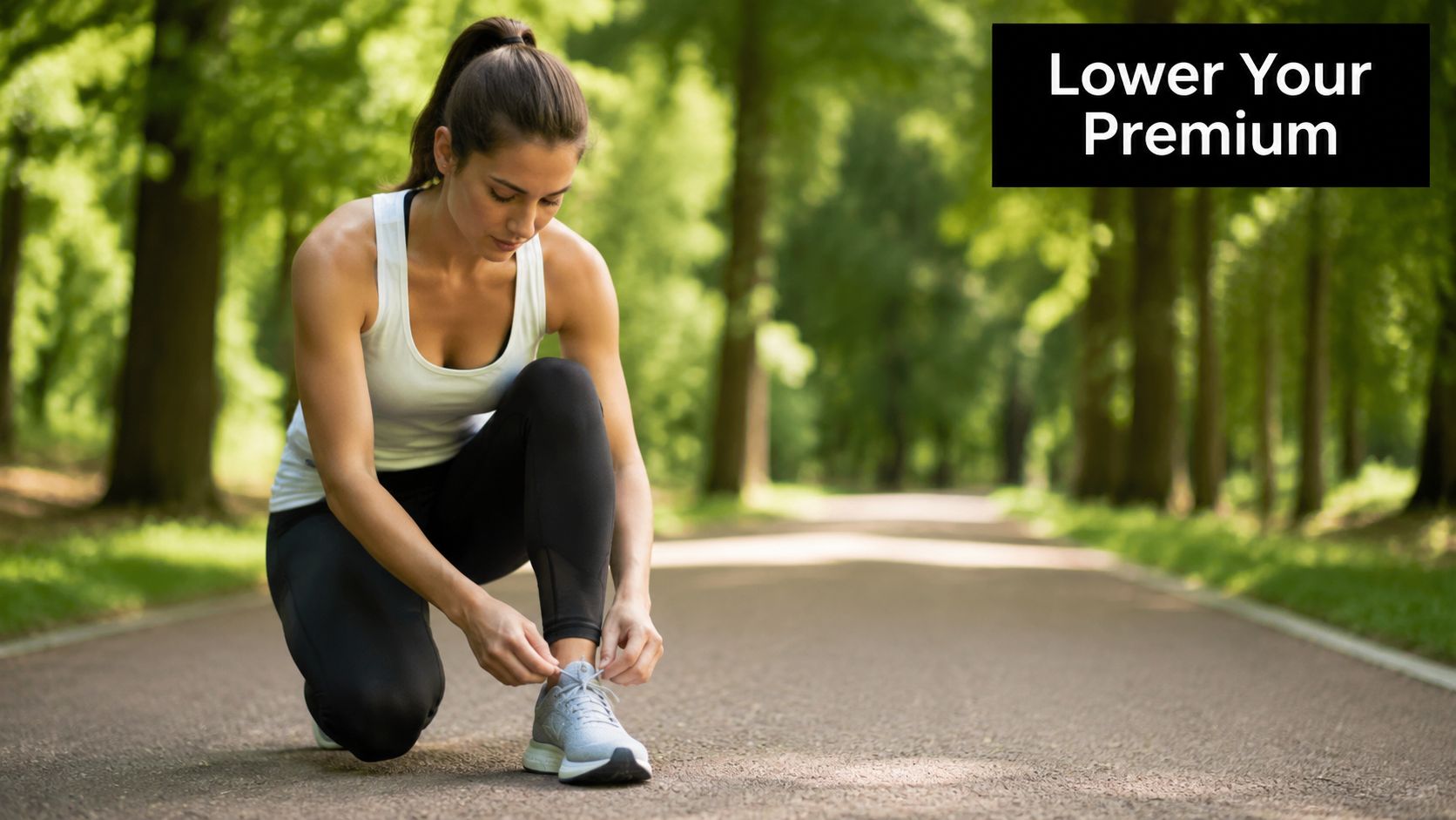A fit woman tying her athletic sneakers on a paved forest path while preparing for a run.
