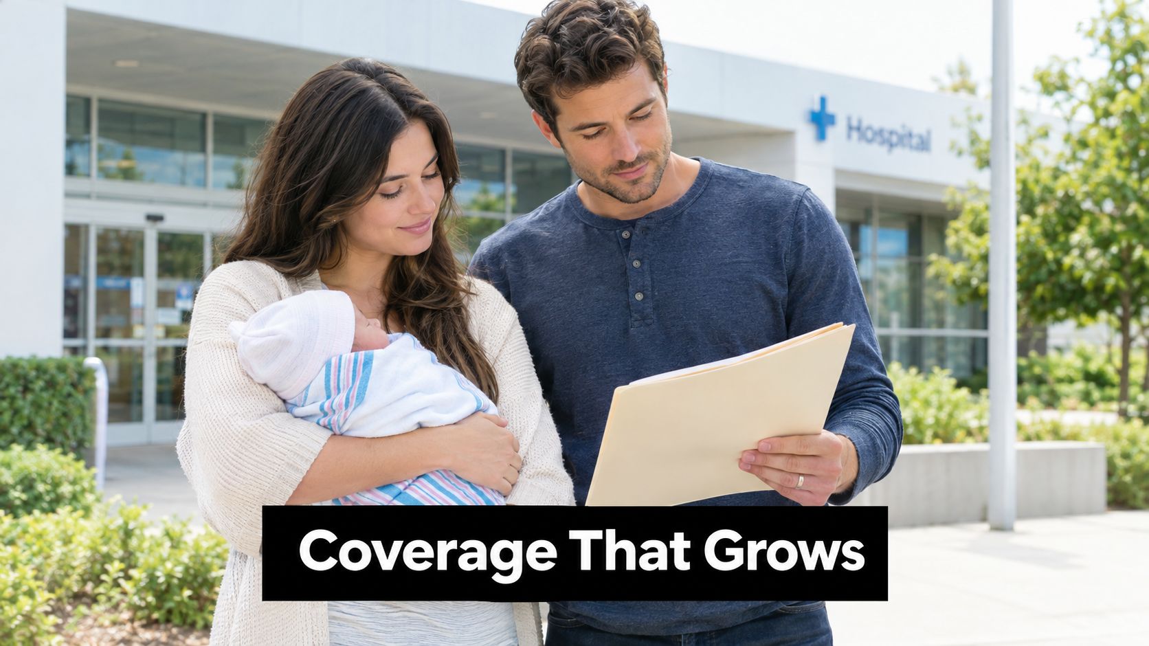 A happy new couple standing outside a hospital holding their newborn baby and looking at insurance documents.